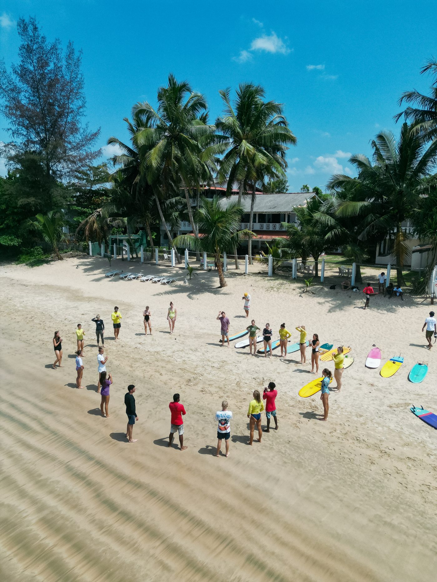 Aerial view of the tribe gathered on the beach with boards