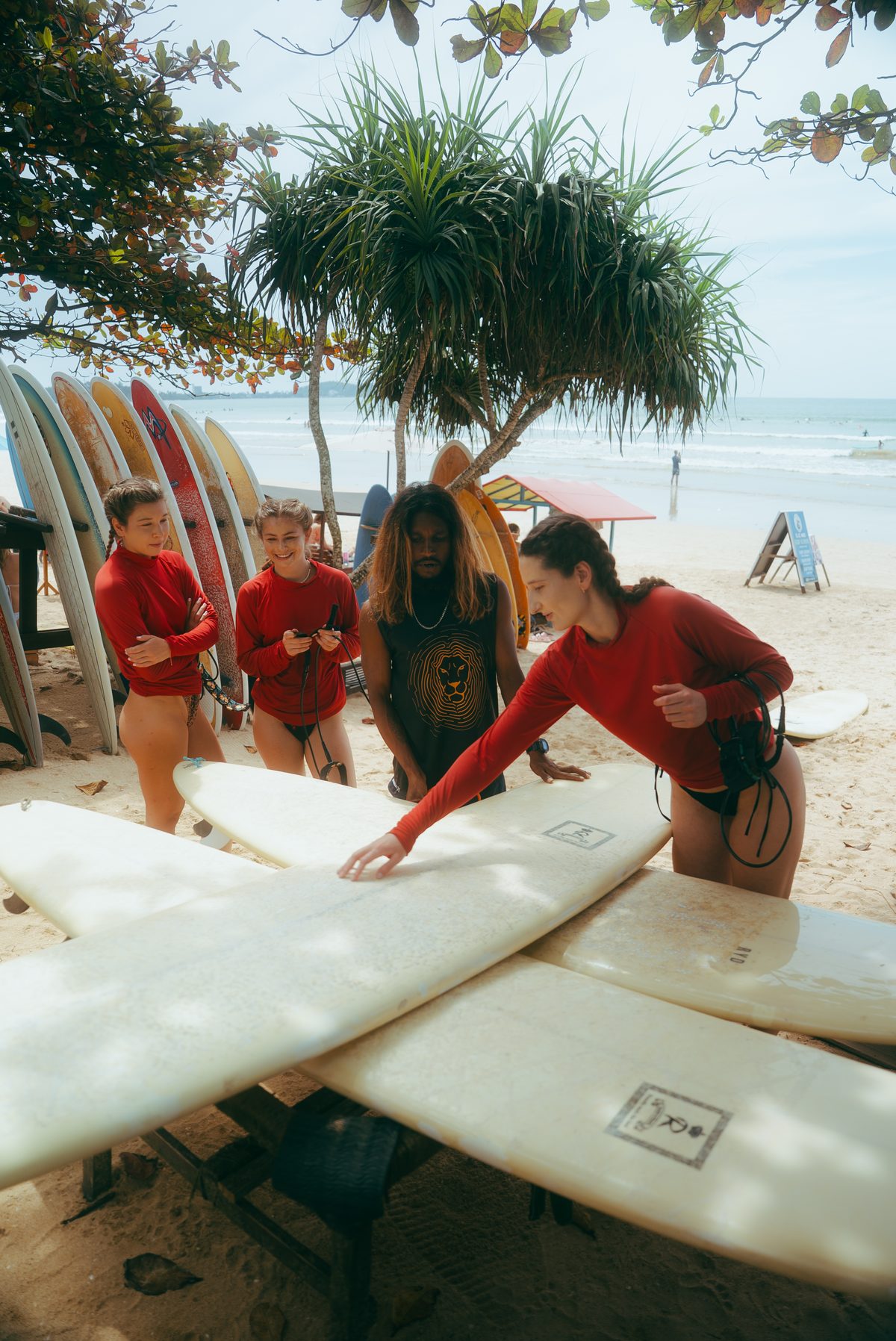 A surf coach talking the tribe through boards on the beach